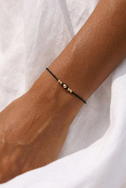 minimalistinė juodo siūlo apyrankė su auksiniais karoliukais. Apyranke su virvelemis, tinka nesioti kasdienai. 